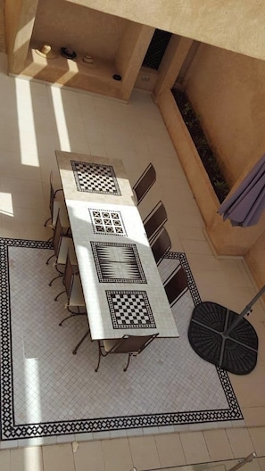 Un comedor con una mesa larga y sillas, piso estampado y ventilador de techo.