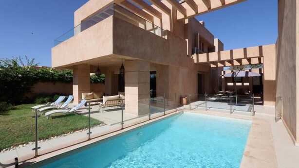 A modern poolside area with a clear pool, lounge chairs, and a pergola structure. - Villa Firdaous (Marrakech)