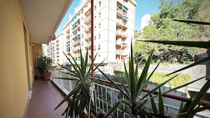 A balcony with potted plants, a tiled floor, and a view of a multi-story building with balconies. - Lussuosa Dimora Fiumara (Genoa)