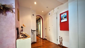 A hotel hallway with wooden flooring, a radiator, a coat rack, and a framed picture on the wall. - Lussuosa Dimora Fiumara (Genoa)