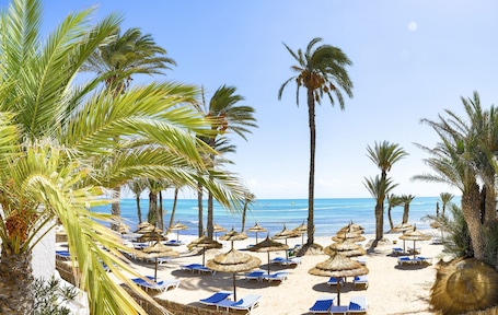 On the beach, white sand, sun loungers, beach umbrellas