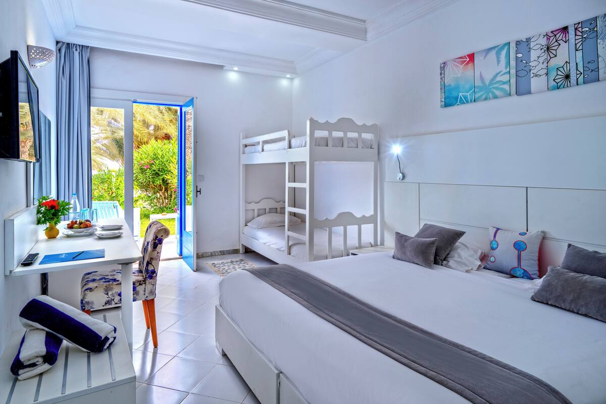 A bedroom with a bunk bed, a desk with a chair, a TV, and a painting on the wall.