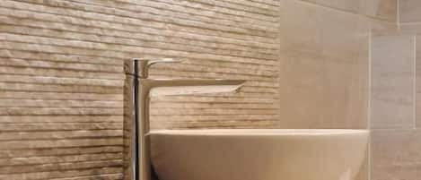 Un baño con un espejo redondo, un lavabo blanco y un tocador de madera.