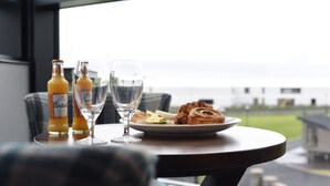 A table with two bottles of Beaujolais wine, two glasses, and a plate with pastries and bread. - Golflinks Hotel (Portrush)