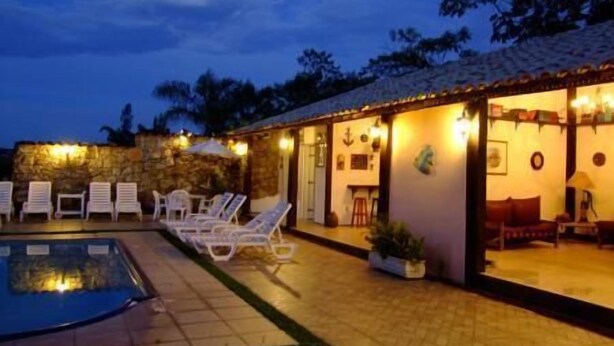 A poolside area with lounge chairs and a stone wall. - Hospedaria da Villa (Tiradentes)