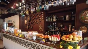 A bar area with a variety of bottles, a clock, and a fruit display. - Hospedaria da Villa (Tiradentes)
