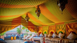 A tented room with a patterned ceiling, a bed with pillows, a small table, and a hanging lantern. - Riad Dar Mamouni (Marrakech)