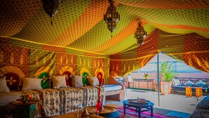 A tented room with patterned fabric walls, a sofa, a coffee table, and a view of the outside. - Riad Dar Mamouni (Marrakech)