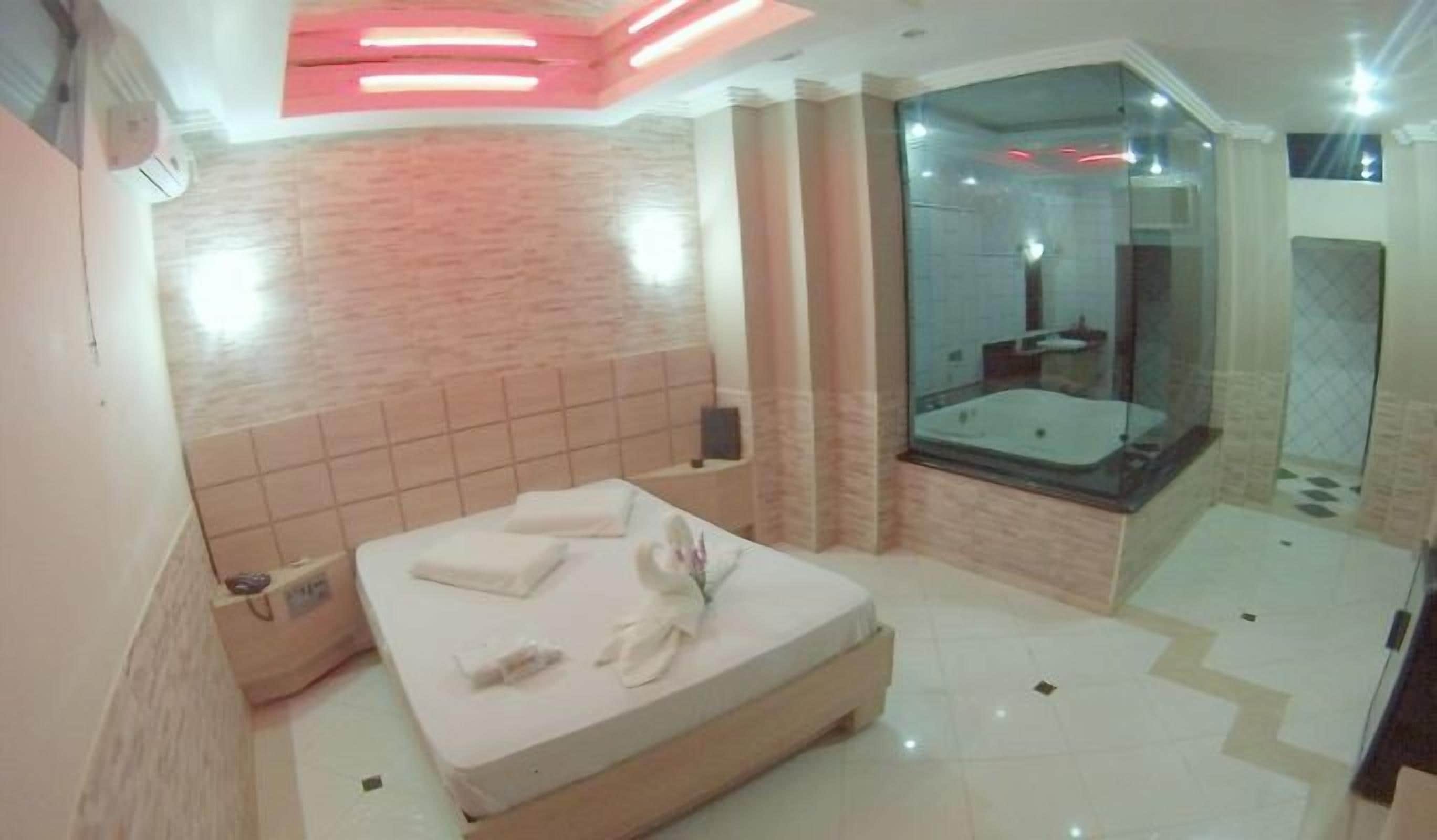 Un baño moderno con una bañera grande, ducha envuelta en vidrio y una cama bien hecha.