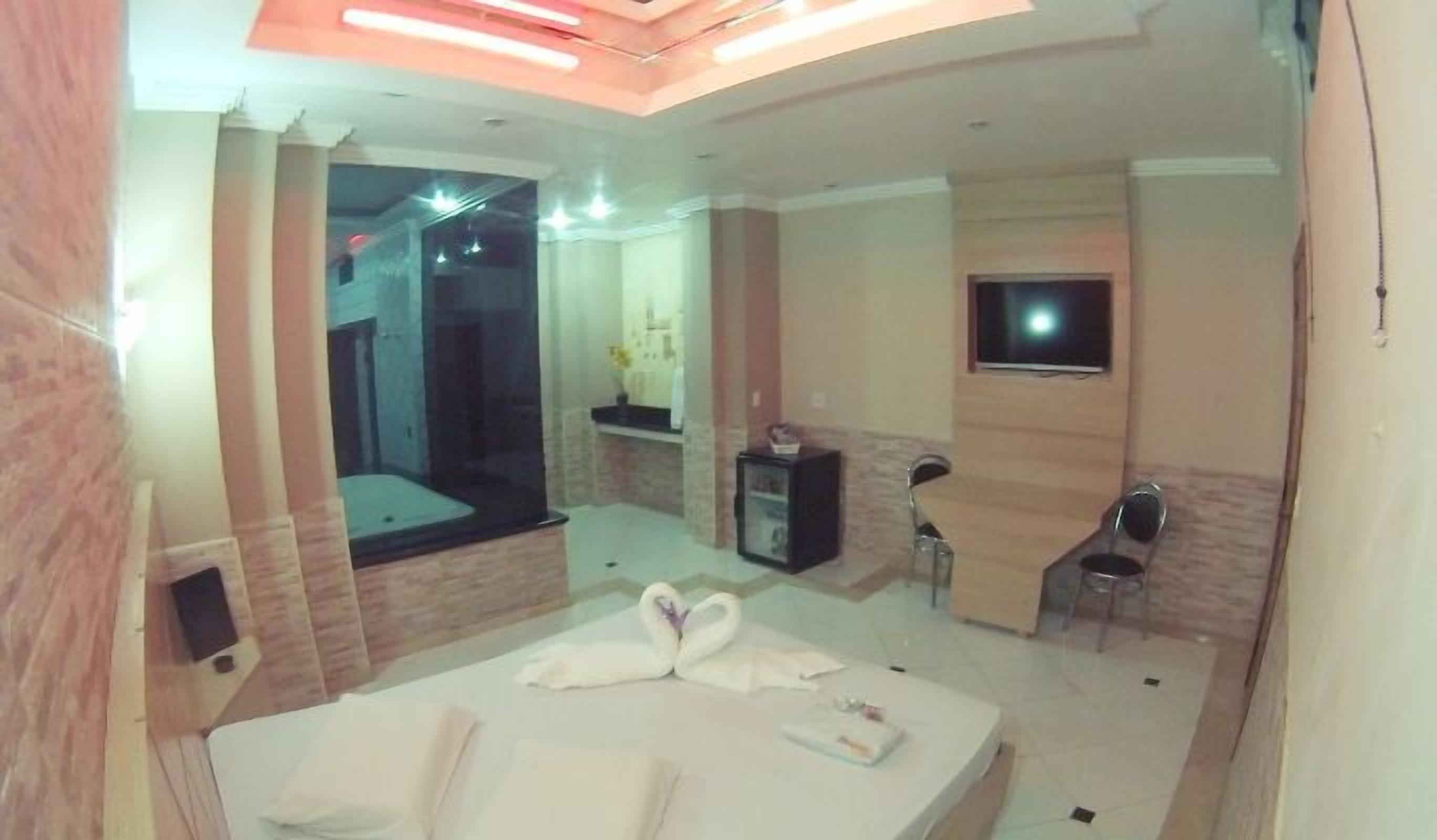 Una habitación de hotel moderna con una cama, un televisor, una ducha y una pequeña mesa.