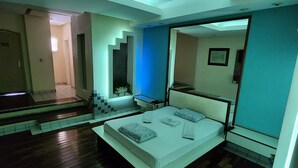 Un dormitorio moderno con tragaluz, una cama con toallas ordenadas y una escalera que sube a un nivel superior.