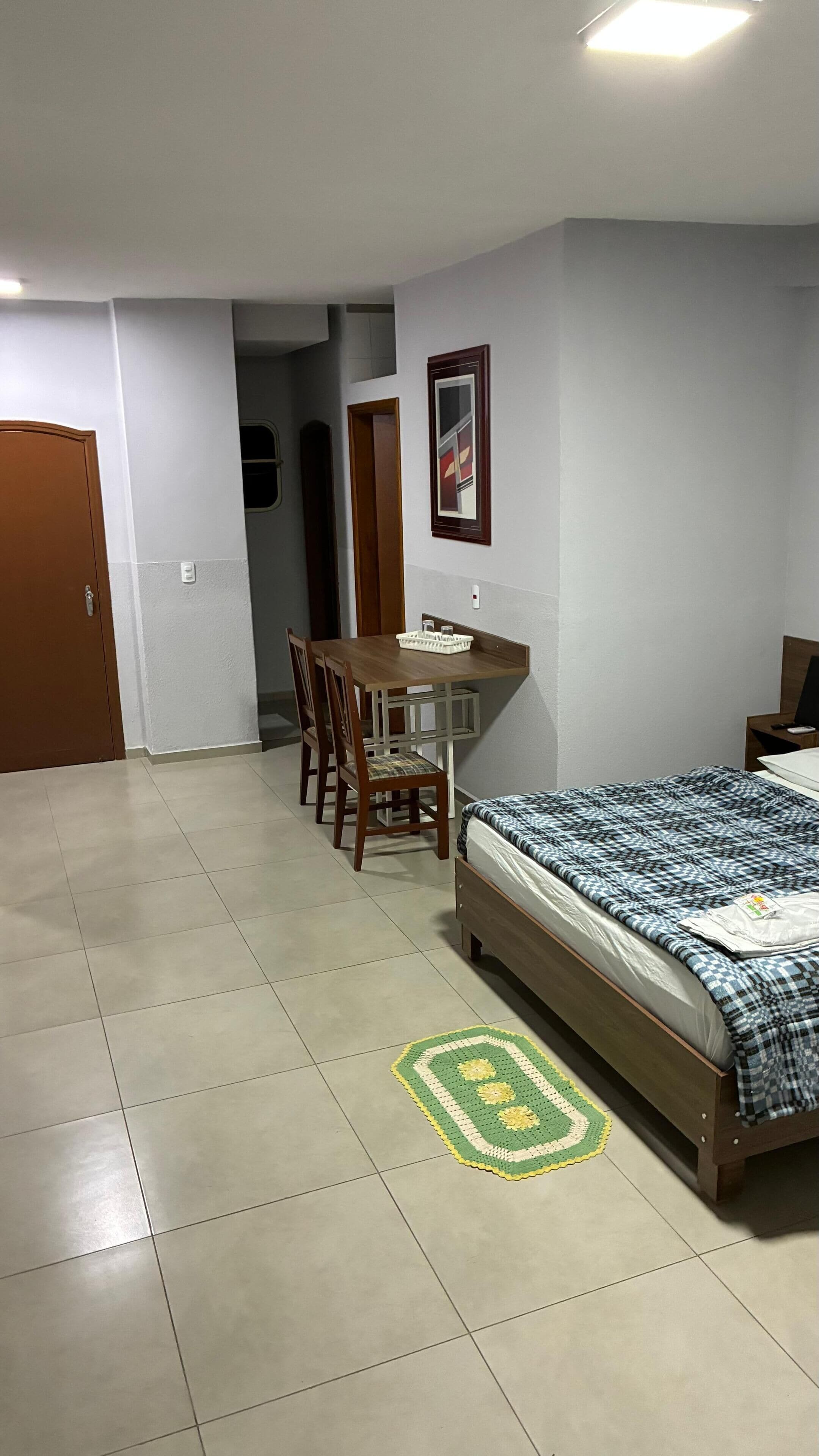 A bedroom with a bed, a desk, and a chair.