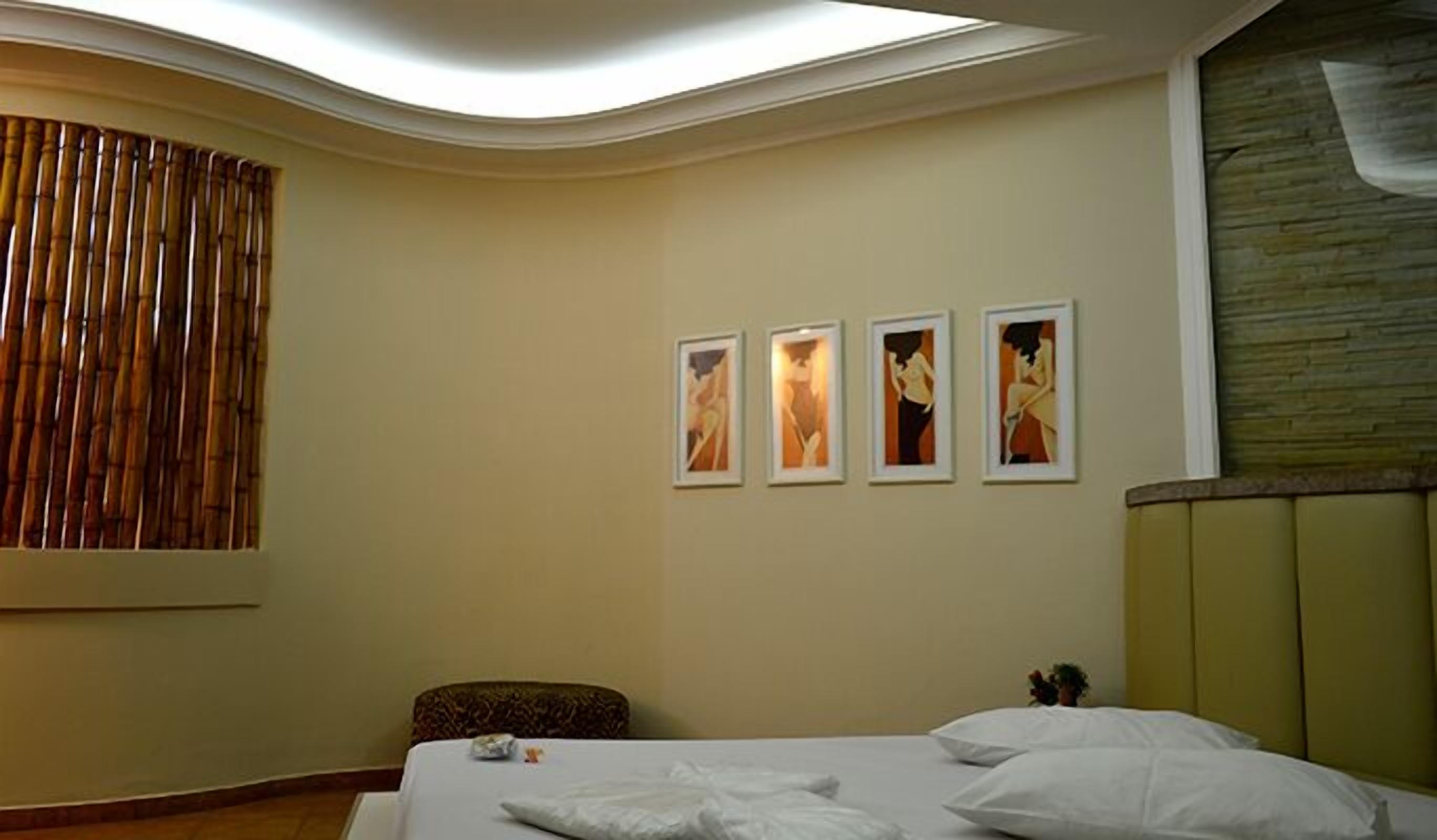 Una habitación de hotel con una cama, una silla y tres cuadros enmarcados en la pared.