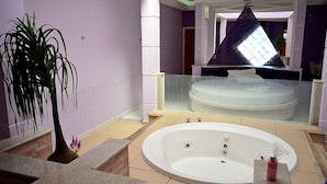 Un baño con una bañera grande, un espejo y una planta en maceta.