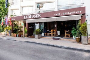 A building with a sign reading "LE MUSEE CAFÉ - RESTAURANT" and a visible entrance with outdoor seating. - Hôtel Le Musée (Rabat)