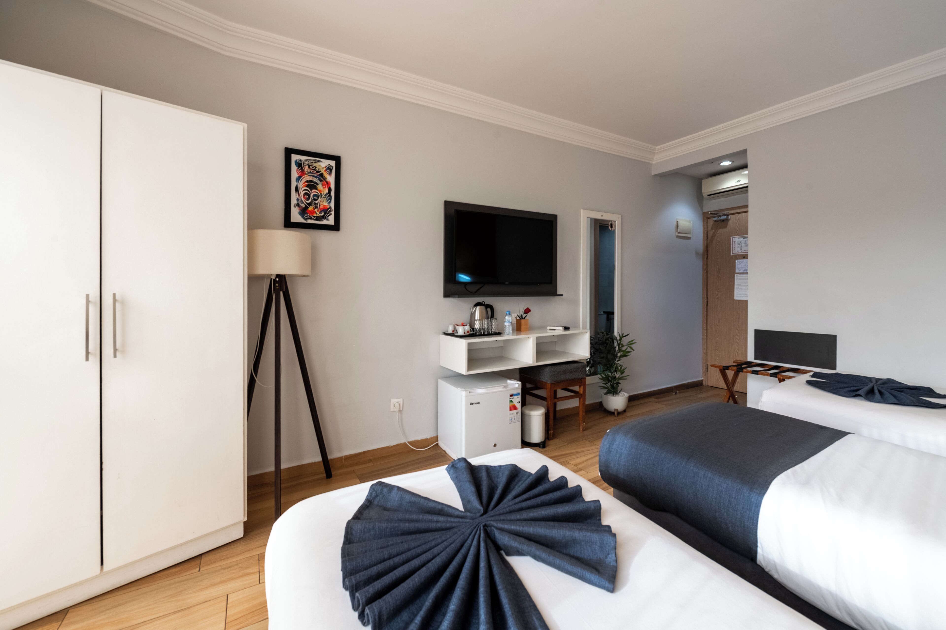 A hotel room with a bed, a desk, a television, and a wardrobe.