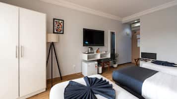 A hotel room with a bed, a desk, a television, and a wardrobe.