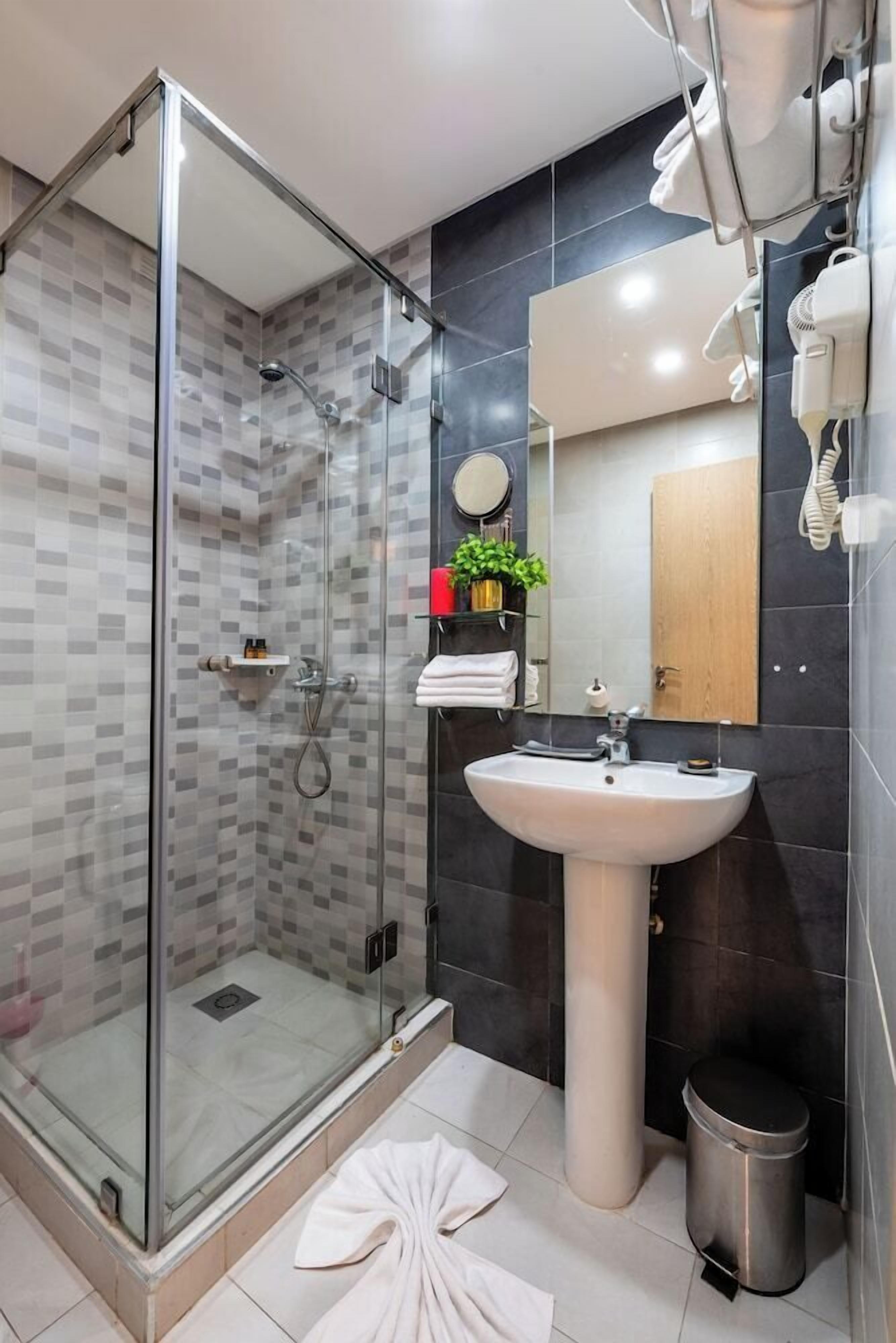 Un baño moderno con cabina de ducha de vidrio, lavamanos, espejo y toallero.