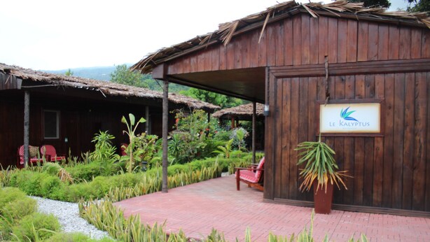 Un bâtiment en bois avec une enseigne indiquant « Le Kalypthus ». On y voit des chaises rouges à l’extérieur et un pot de fleurs à proximité.