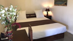 Une chambre d’hôtel avec un lit, une lampe de chevet, un appareil de climatisation et un tableau au mur.