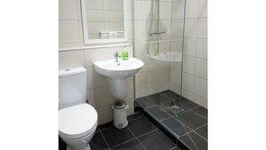 A bathroom with a toilet, a pedestal sink, a glass shower enclosure, and a mirror above the sink. - Belfast House (Cookstown)