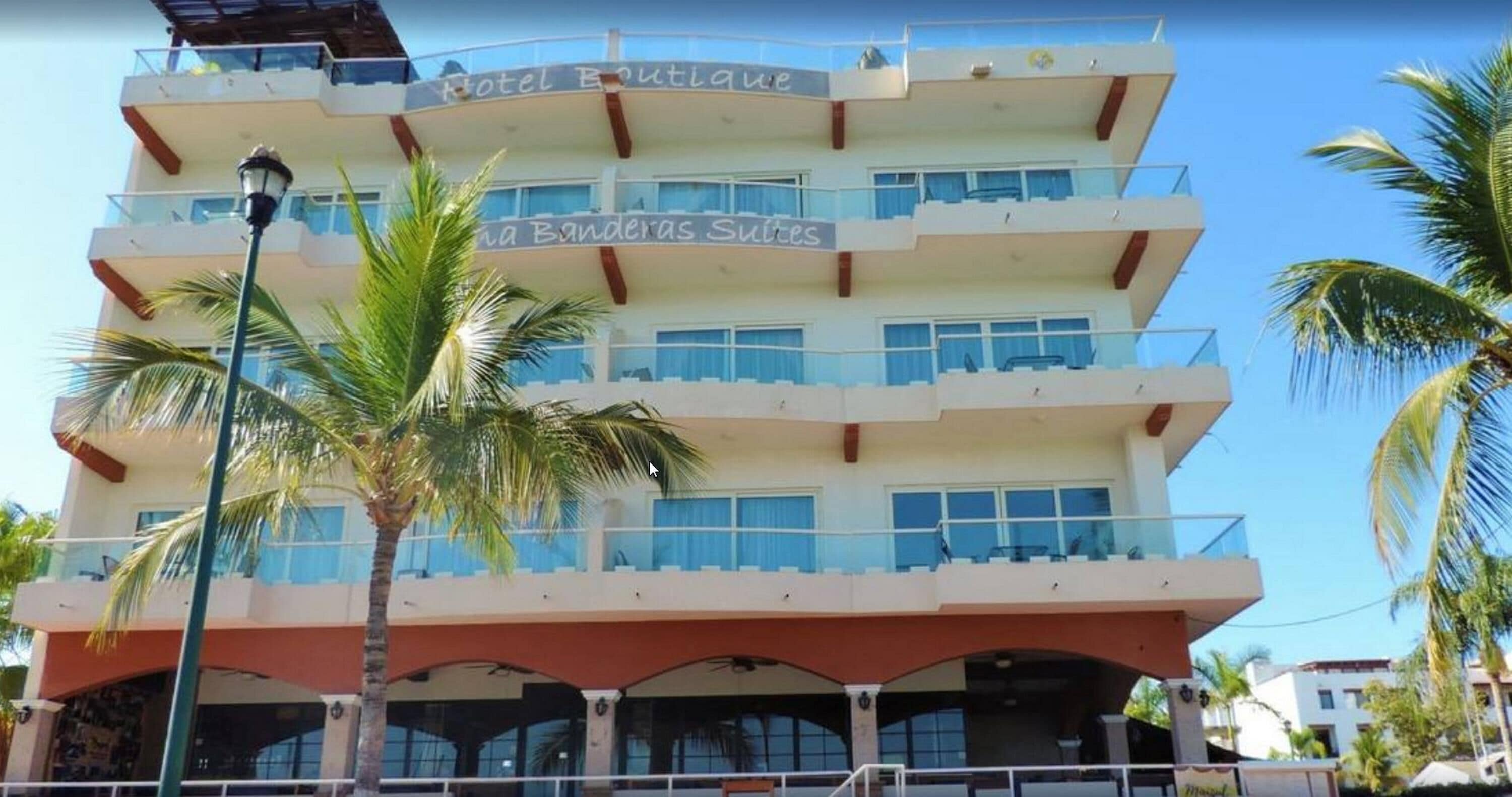 A multi-story hotel with balconies and a sign reading "Hotel Boutique Banderas Suites".