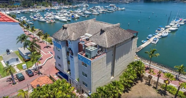 A multi-story building with a thatched roof, located near a marina with numerous boats docked.