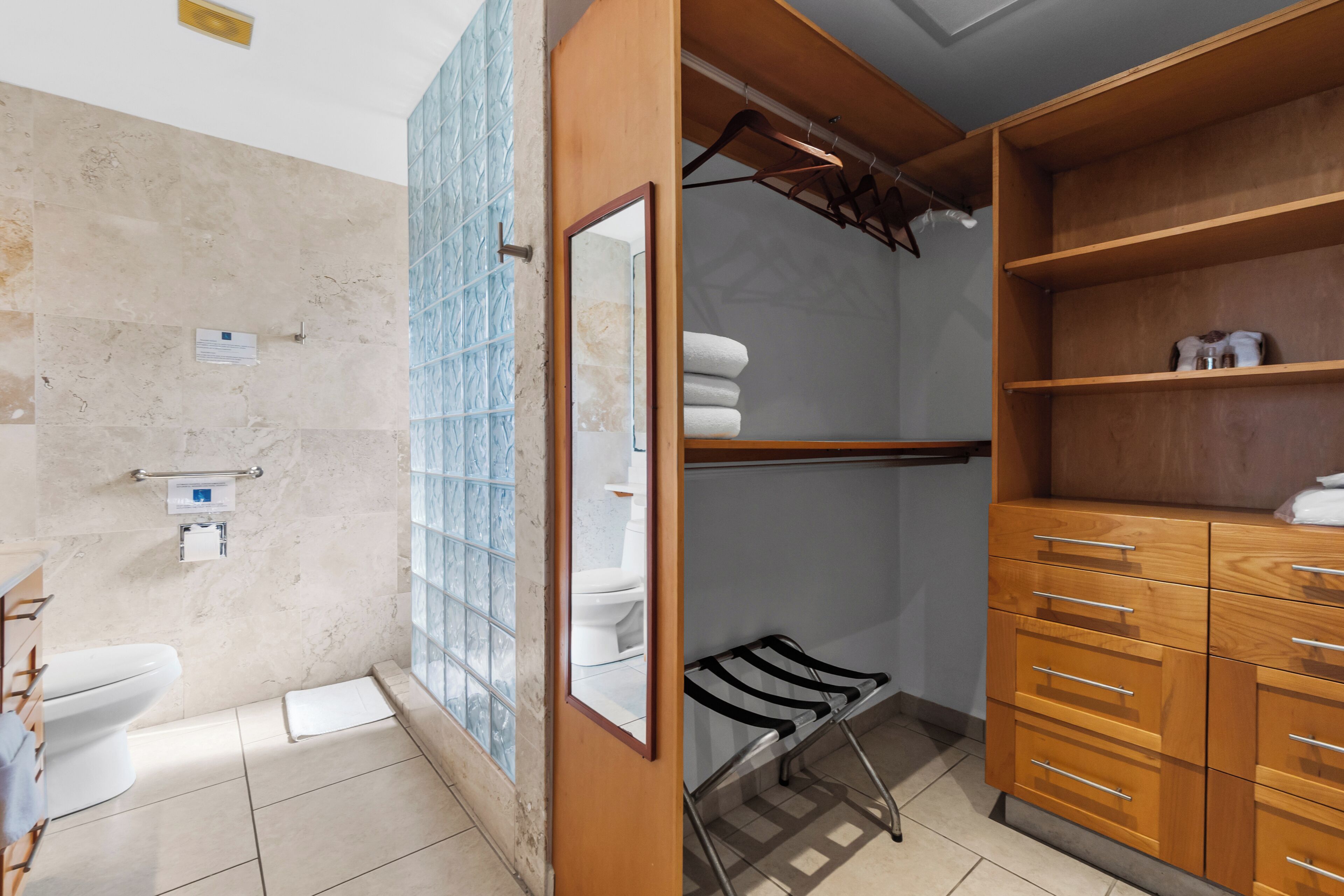 A bathroom with a toilet, a shower, a towel rack, and a wooden cabinet.