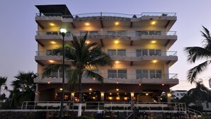 Un hotel de varios pisos con balcones, mobiliario exterior y un cartel que dice "Hotel Boutique La Bandera Suites".