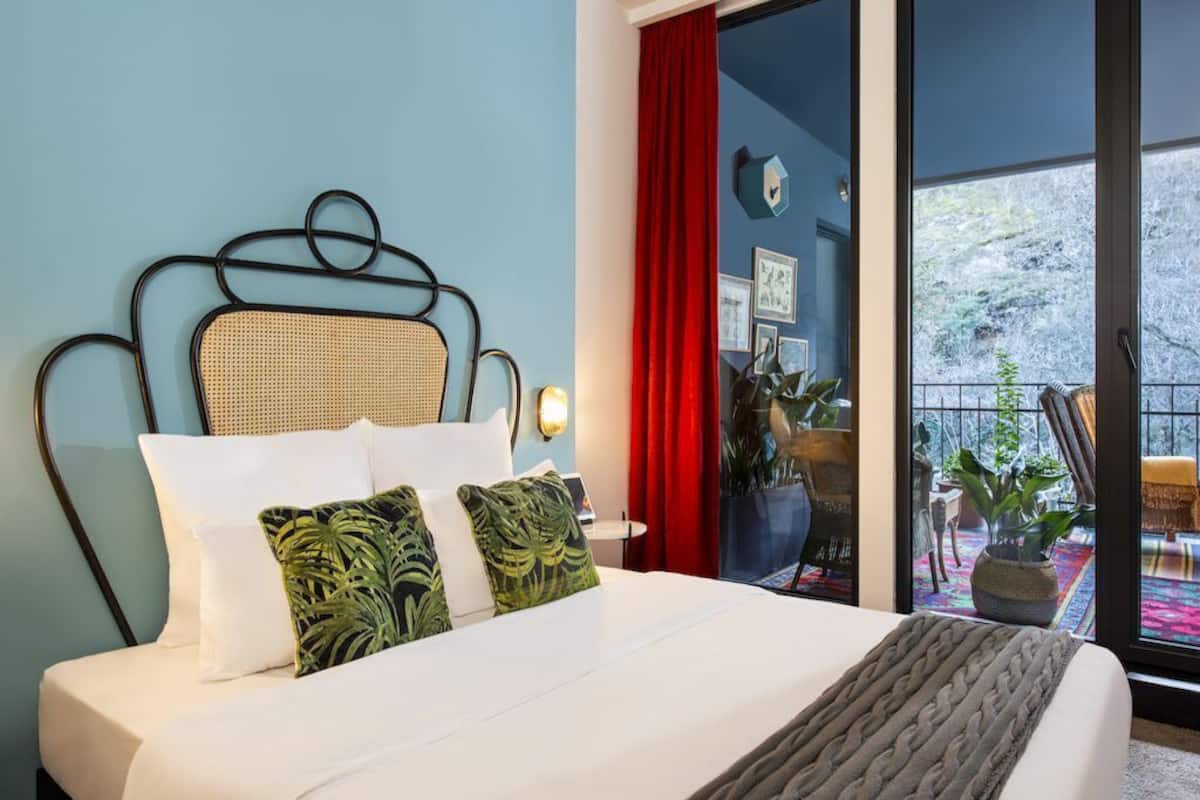 A bed with a woven headboard, white bedding, and two green pillows.