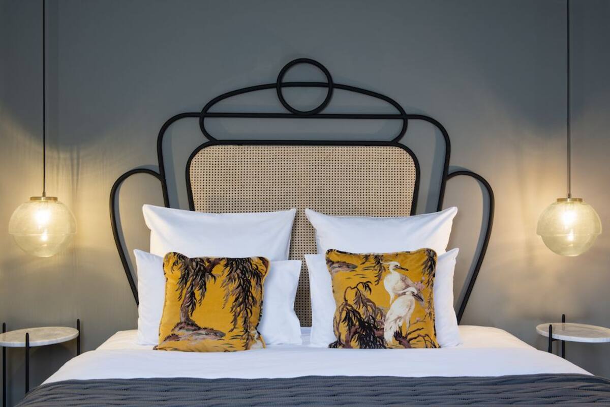 A bed with a headboard, two bedside tables, and two wall-mounted lamps.