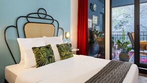 Una cama con cabecera de mimbre, ropa de cama blanca y almohadas estampadas en verde.
