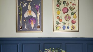 Una mesa de comedor dispuesta con platos, vasos y un jarrón de flores.