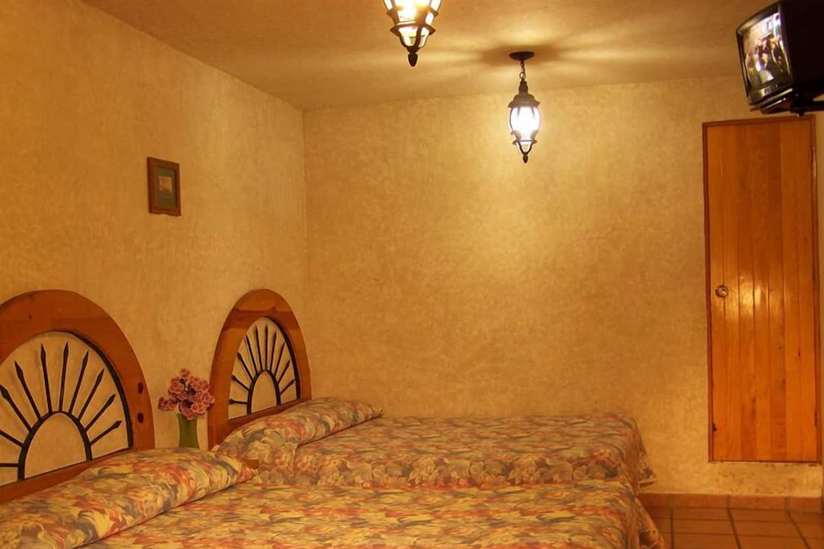 Un dormitorio con dos camas, un armario de madera y una televisión en la pared.