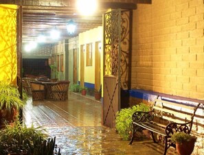 A wet outdoor corridor with a bench and potted plants. - Hotel Posada La Loma (Tapalpa)