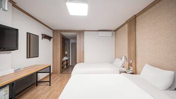 Una habitación de hotel con dos camas, un escritorio, un televisor y una puerta que da a un baño.