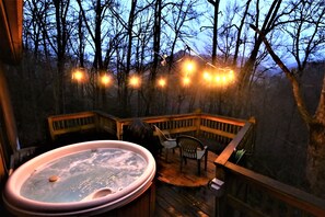 Een hottub op een houten terras met uitzicht op een bebost gebied.