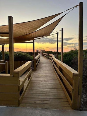 A wooden boardwalk leading to a covered area with a view of the sunset. - Large 1BD, 1BA Ocean Front Complex, Ground Floor, Free Wifi, Hdtv, Large pool (St Augustine)