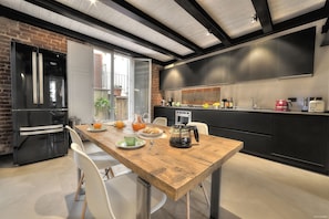 A modern kitchen with a wooden table, black cabinets, and a brick wall. - Stone Walls, Luxury, Modern, High End , Perfectly Silent Condo. 1 min from Duomo (Firenze)