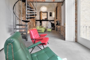 A modern interior with a spiral staircase, green and red chairs, and a brick wall. - Stone Walls, Luxury, Modern, High End , Perfectly Silent Condo. 1 min from Duomo (Firenze)