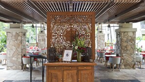 Un espace extérieur aménagé pour les repas, avec des piliers en pierre, des tables et des chaises en bois.