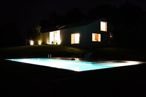 Een modern huis met een zwembad in de nacht.