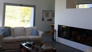 A modern living room with a high ceiling, a sofa set, a fireplace, and a large window. - 4 bedroom house with private pool (Celorico de Basto)