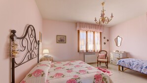 Une chambre à coucher comprenant un lit, une chaise, une commode, un radiateur et un lustre.