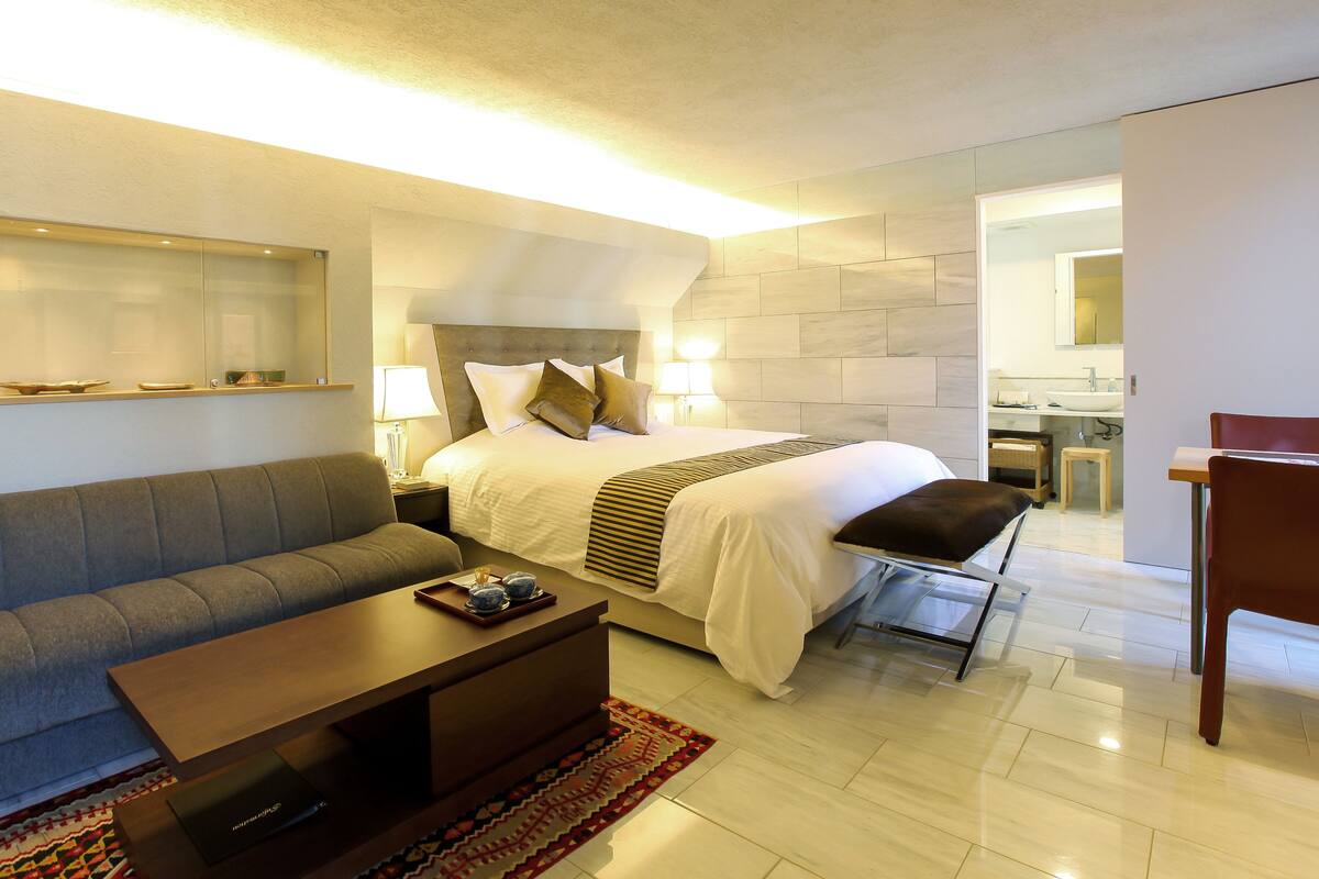 Una habitación de hotel moderna con una cama, un sofá, una mesa de centro y un escritorio.