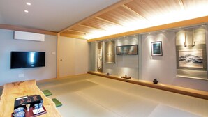 Een modern interieur met een houten tafel, een flatscreen televisie en een wand met ingelijste kunstwerken.