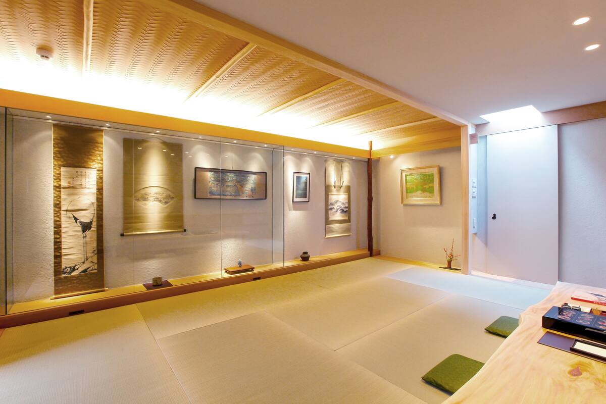 Una habitación japonesa tradicional con suelo de tatami, puertas correderas y obras de arte en las paredes.