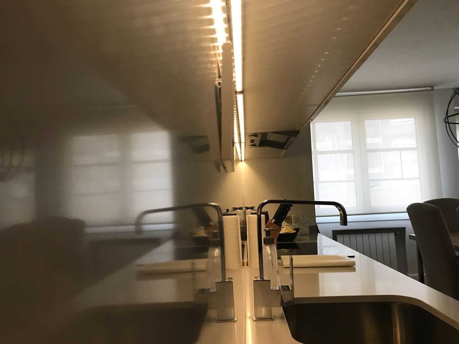 Una cocina moderna con un lavamanos de acero inoxidable, horno empotrado y una ventana que proporciona luz natural.
