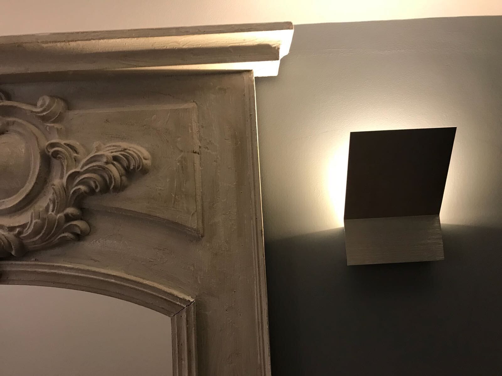 Parede com luminária e moldura decorativa.