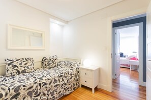 Un dormitorio con cama, mesita de noche y una puerta que da a otra habitación.